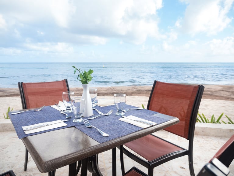 Table with dinner setting at outdoors restaurant near tropical sea