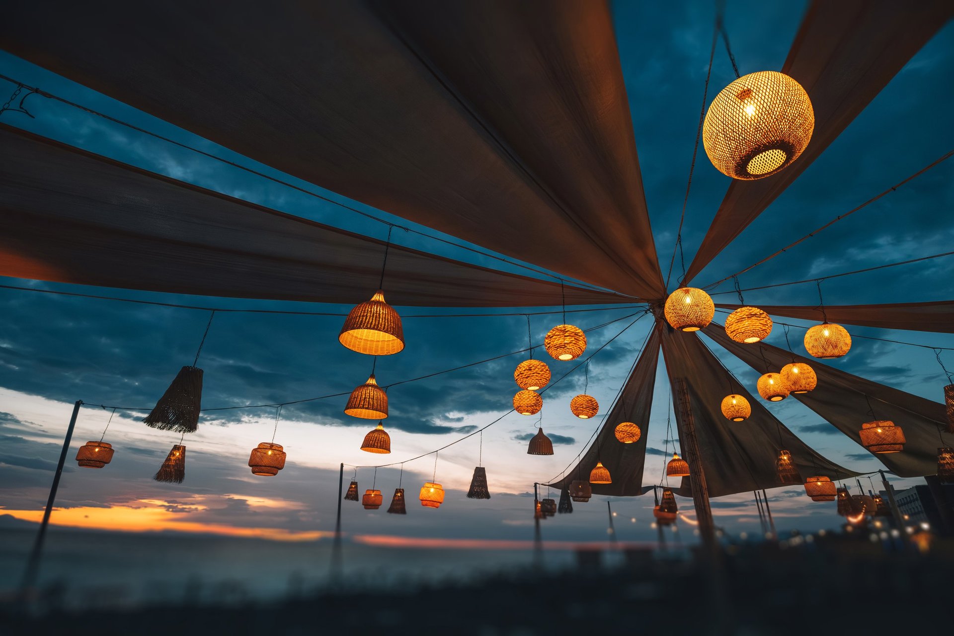Warm light from hanging lanterns creates a magical atmosphere at an outdoor evening in beach bar