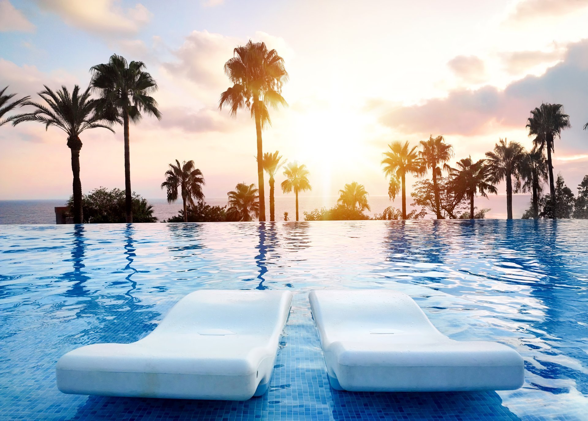 A tranquil sunset view over an infinity pool with palm trees