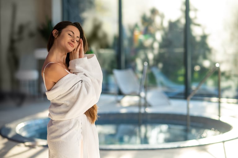 Relaxed and enjoyed. Woman in white bath robe standing near the pool in a spa center